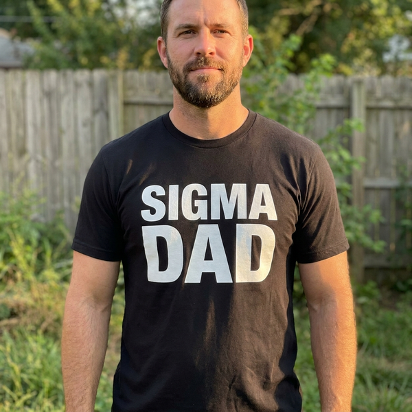 Man wearing black Sigma Dad statement t-shirt in backyard