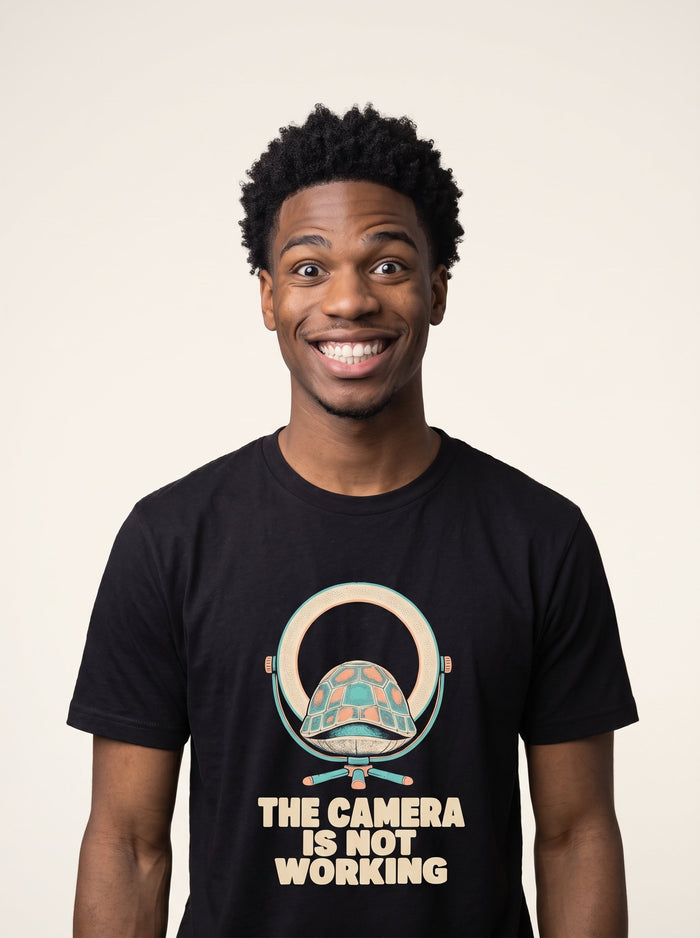 The Camera Is Not Working tee worn front view, black unisex tee, tortoise sitting in a ring light