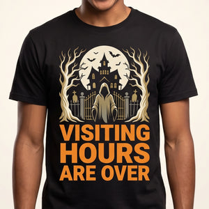 Visiting Hours Are Over tee worn front view, black unisex tee, haunted house, full moon and hooded figure at a cemetery gate