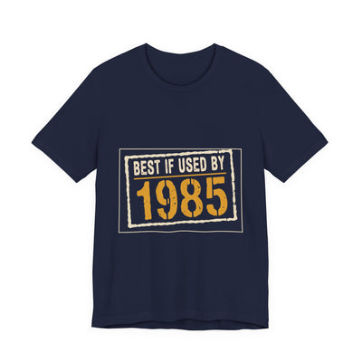 Best If Used By 1985 tee flat front, navy unisex tee, cream expiry stamp, amber year