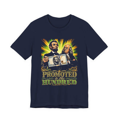 Navy tee printed with a vivid realistic Lincoln holding a hundred-dollar bill with his own face taped on, Franklin glaring, text Promoted To The Hundred