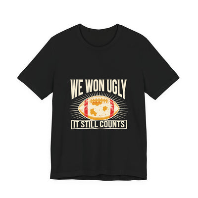 We Won Ugly tee flat front, black unisex tee, mud-caked football badge