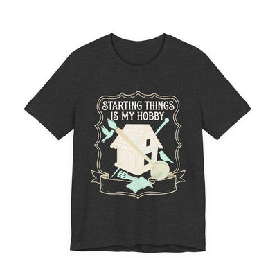 Starting Things Is My Hobby tee flat front, dark grey heather unisex tee, a half-built birdhouse