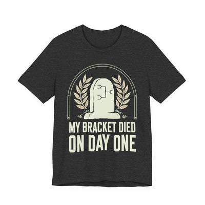 My Bracket Died On Day One tee flat front, dark grey heather unisex tee, headstone with a bracket diagram
