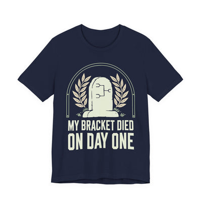 My Bracket Died On Day One tee flat front, navy unisex tee, a headstone with a bracket diagram carved on it