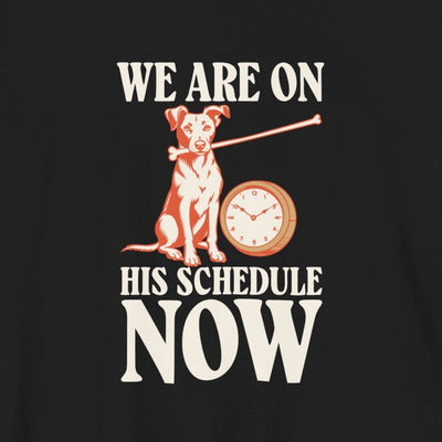 We Are On His Schedule Now tee print close-up, black unisex tee, dog beside a wall clock