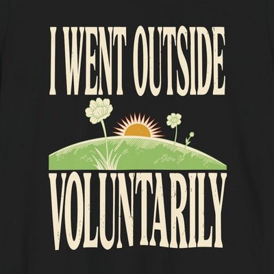 I Went Outside Voluntarily tee print close-up, black unisex tee, sun over a green hill