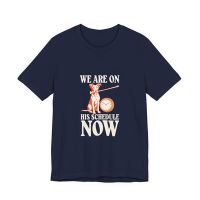 We Are On His Schedule Now tee flat front, navy unisex tee, dog beside a wall clock