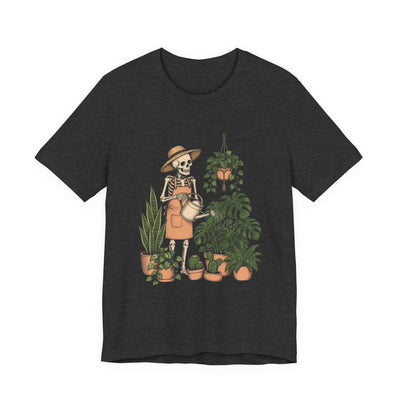 Skeleton Plant Parent tee flat front, dark grey heather unisex tee, skeleton in a sun hat watering a monstera and houseplants