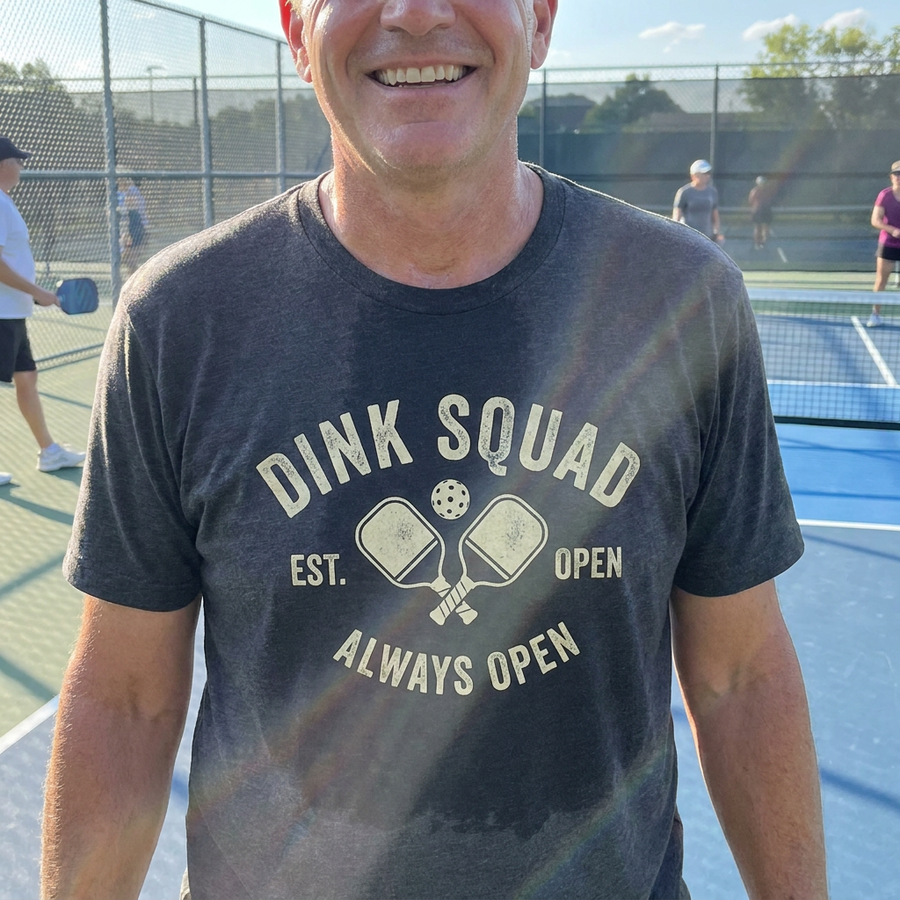 Retro pickleball Dink Squad badge tee on black shirt, worn at outdoor court, lifestyle photo
