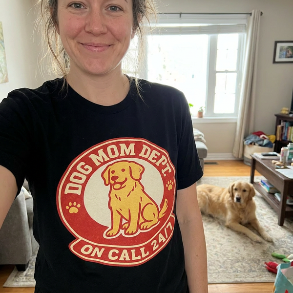 Funny dog mom badge tee reading 'Dog Mom Dept. On Call 24/7' on black shirt, lifestyle photo