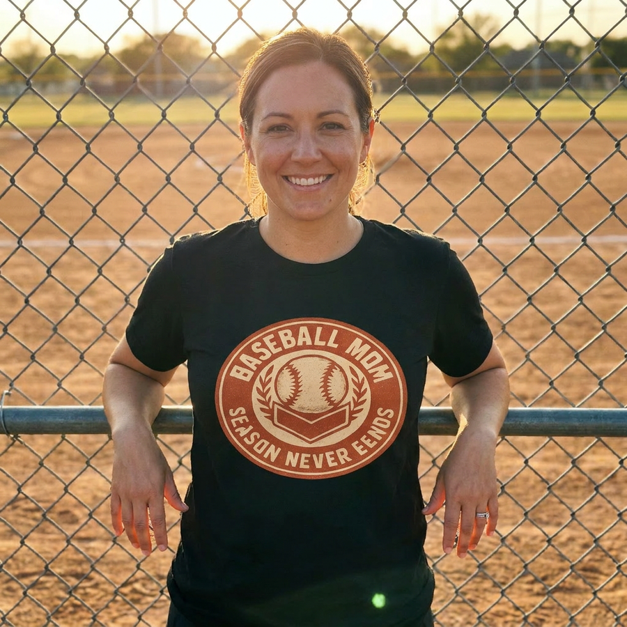 Baseball mom wearing sideline crew vintage badge tee at the diamond fence, golden hour, lifestyle photo