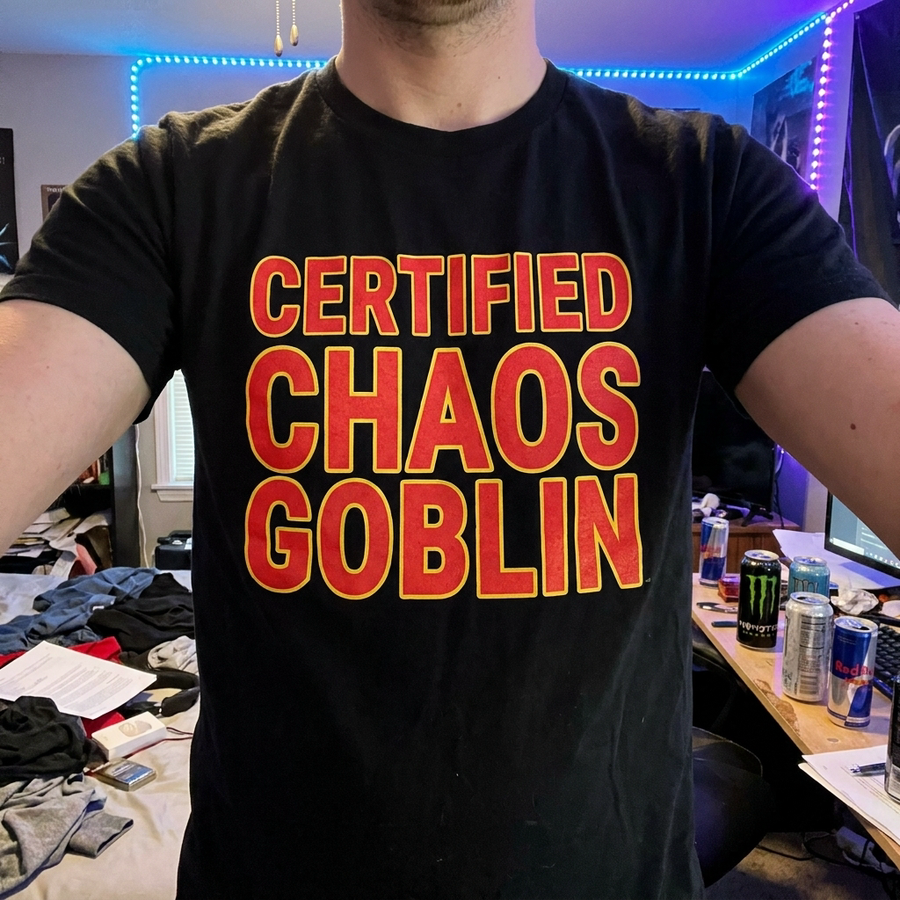 Certified Chaos Goblin badge tee on model, chest-up, bold red graphic on black shirt