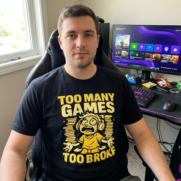 Man wearing Too Many Games Too Broke black t-shirt at gaming desk, design fully visible