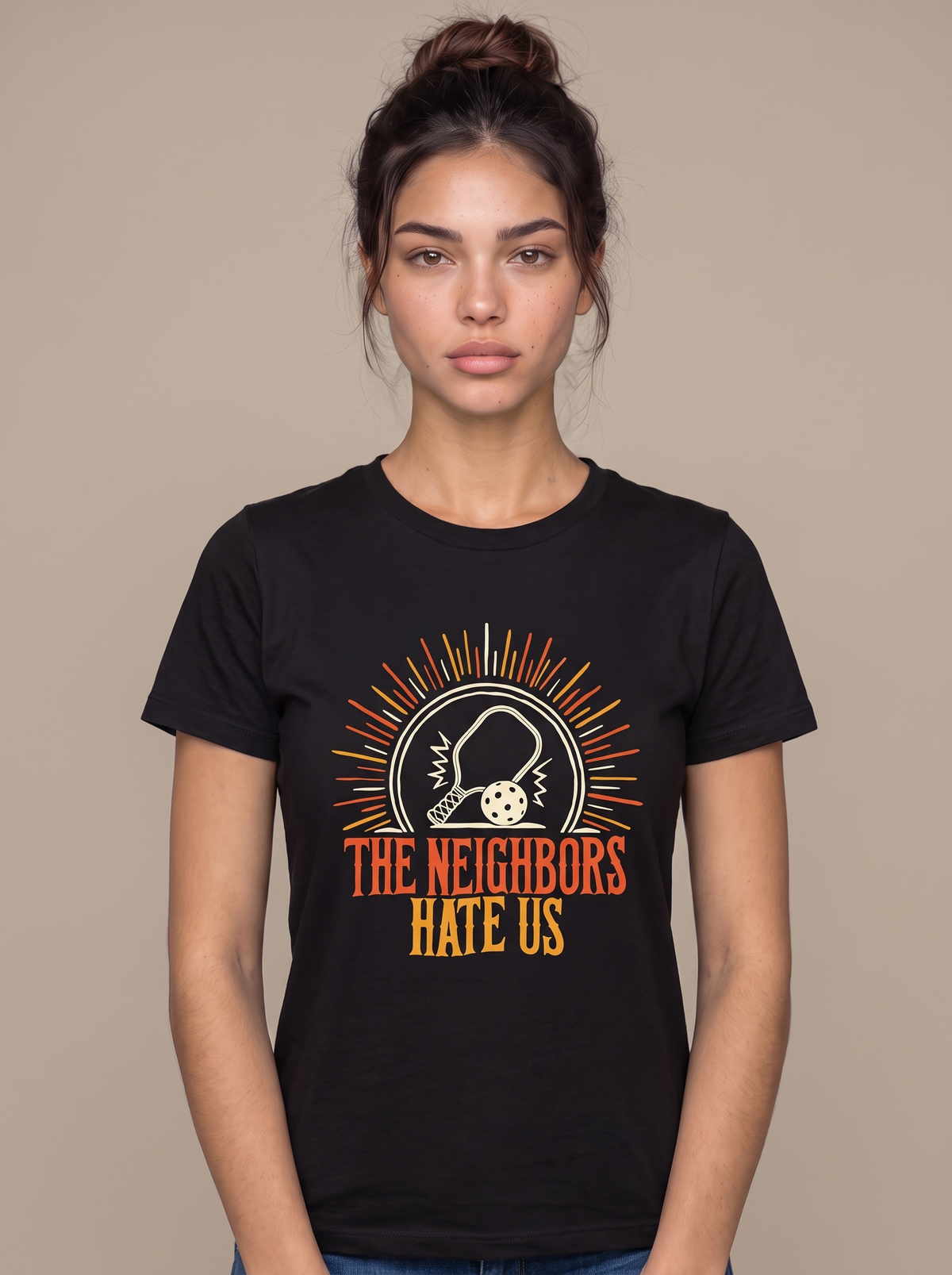 The Neighbors Hate Us tee worn front view, black unisex tee, pickleball paddle in a sunburst badge