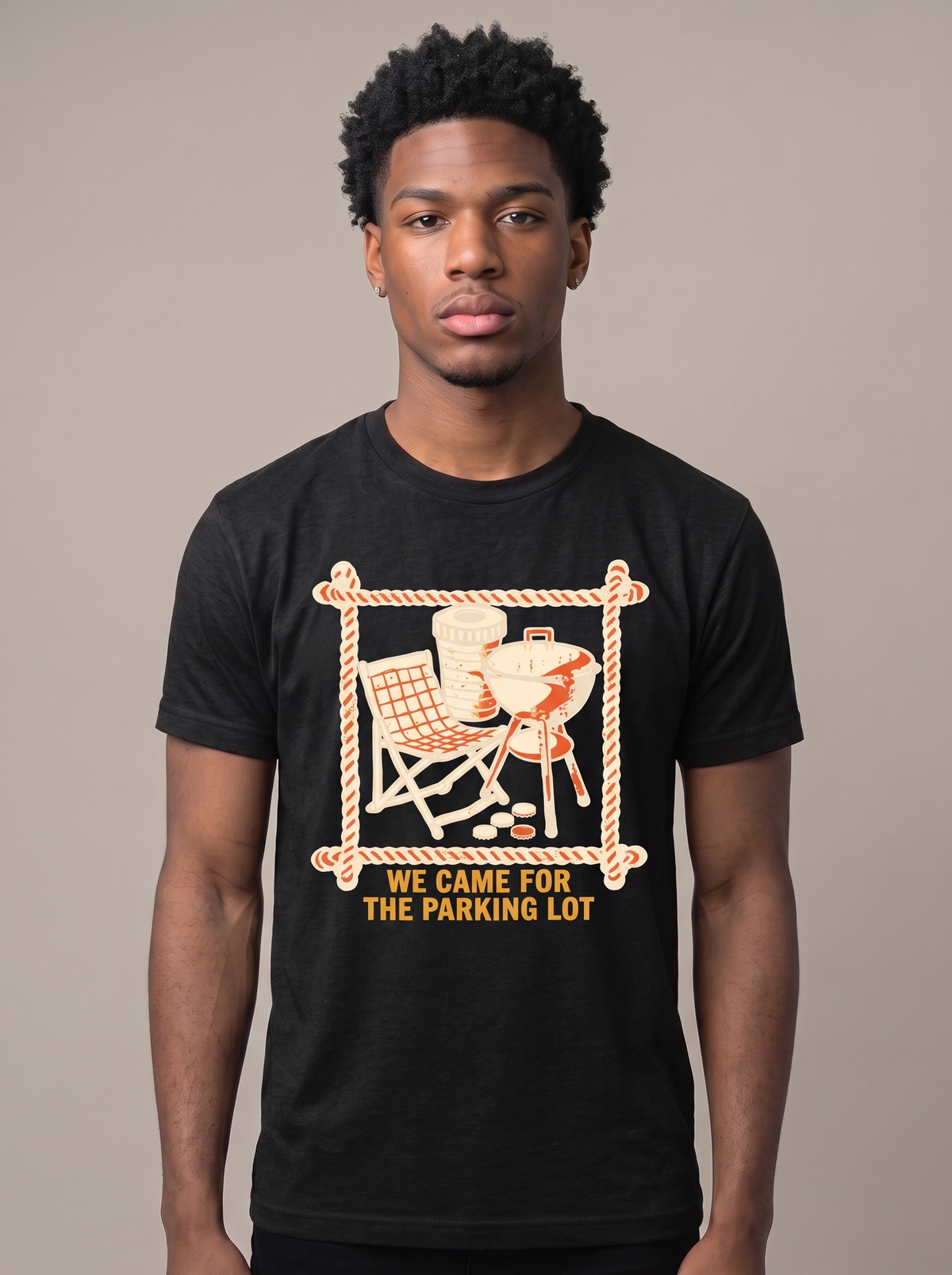 We Came For The Parking Lot tee worn front view, black unisex tee, camp chair and grill crossed behind a stadium cup