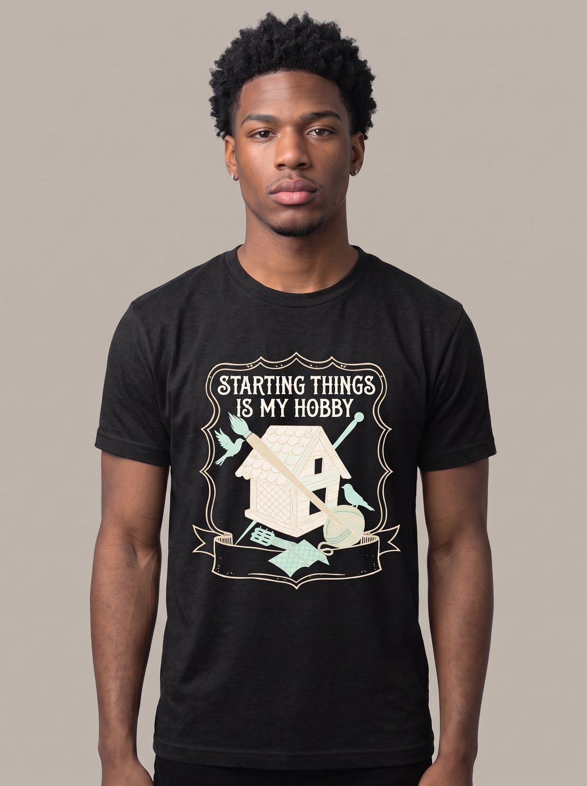 Starting Things Is My Hobby tee worn front view, black unisex tee, a half-built birdhouse with brush and yarn