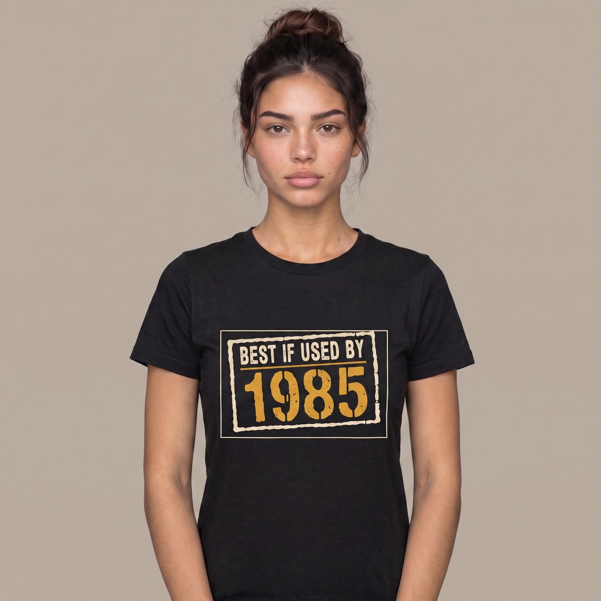 Best If Used By 1985 tee worn front view, black unisex tee, cream expiry stamp with an amber year